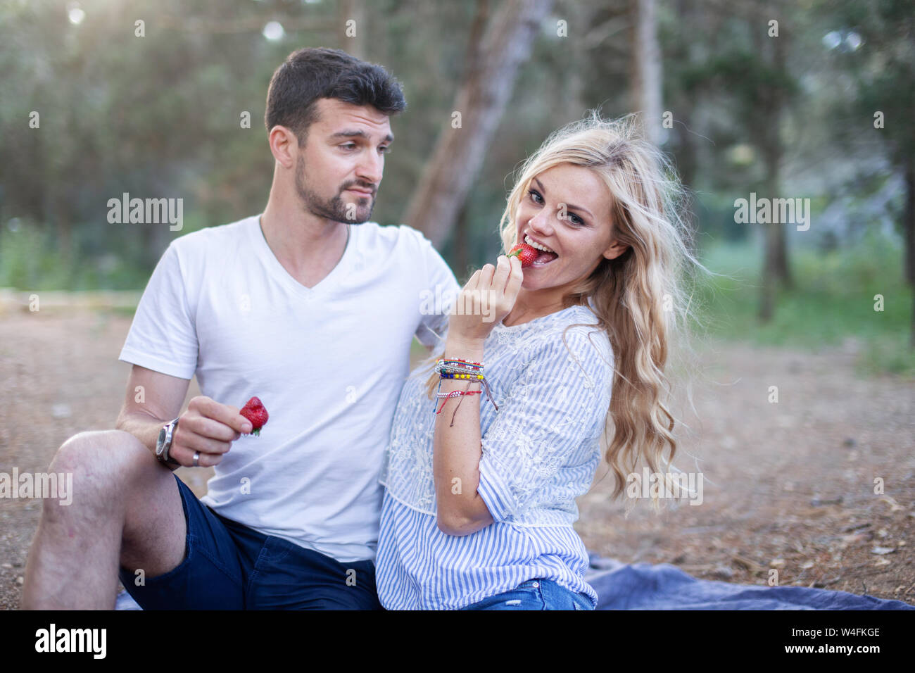 Junge kaukasier Paar Erdbeeren essen auf Picknick in der Natur Stockfoto