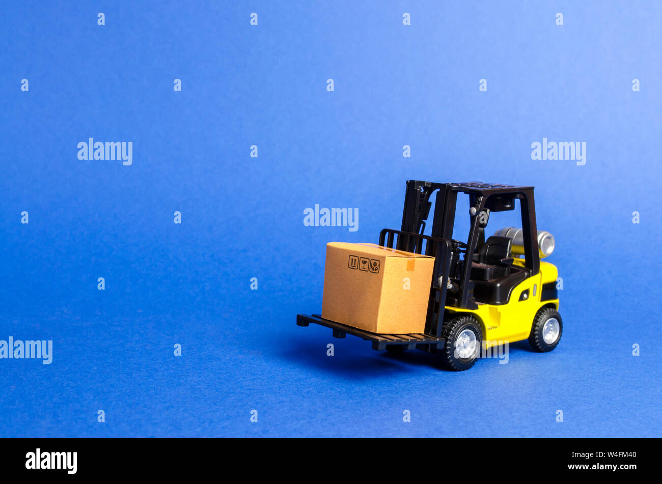Gelbe Gabelstapler mit Karton. Umsatz, Produktion von Gütern. Transport, Lagerung der Fracht. Fracht, die Lieferung von Waren. Stockfoto