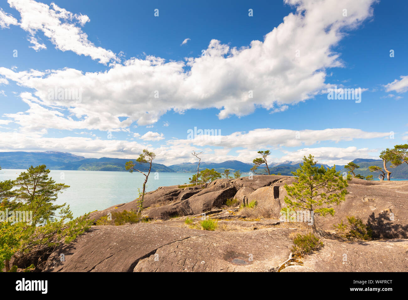 Eine wüste Landschaft in Norwegen bei der Geiranger Fjord im Sommer mit blauem Himmel und weißen Wolken und Felsen im Vordergrund an einem schönen Tag. Stockfoto