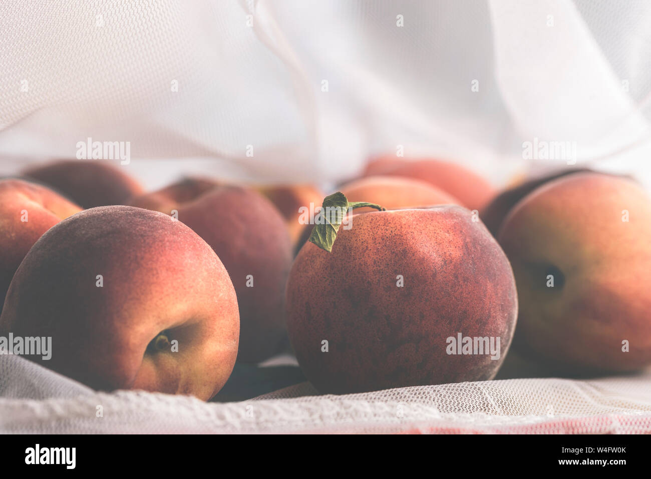 Reife Pfirsiche in eine wiederverwendbare mesh Shopping Bag. Die kunststoffverpackung Konzept reduzieren. Verpackungen aus Kunststoff Management Konzept. Lebensmittel in einem eco Beutel. Stockfoto