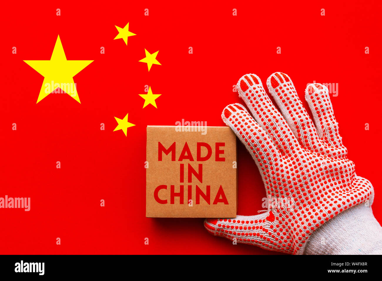 In China hergestellt, Arbeiter mit Schutzhandschuhe holding Karton Produkt Paket über chinesische Nationalflagge. Stockfoto
