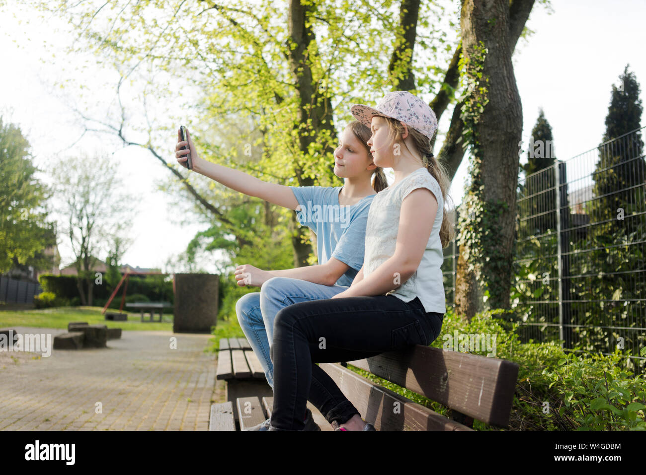Zwei Mädchen sitzen auf einer Parkbank ein selfie Stockfoto