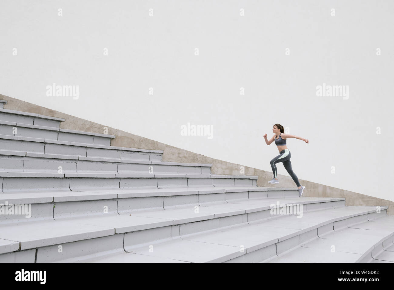 Junge Frau, die auf konkrete Zuschauertribünen Stockfoto