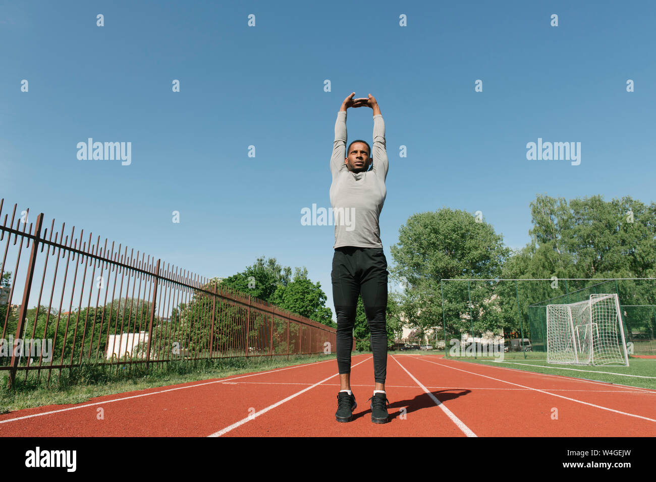 Sportler seine Arme stretching auf Rennstrecke Stockfoto