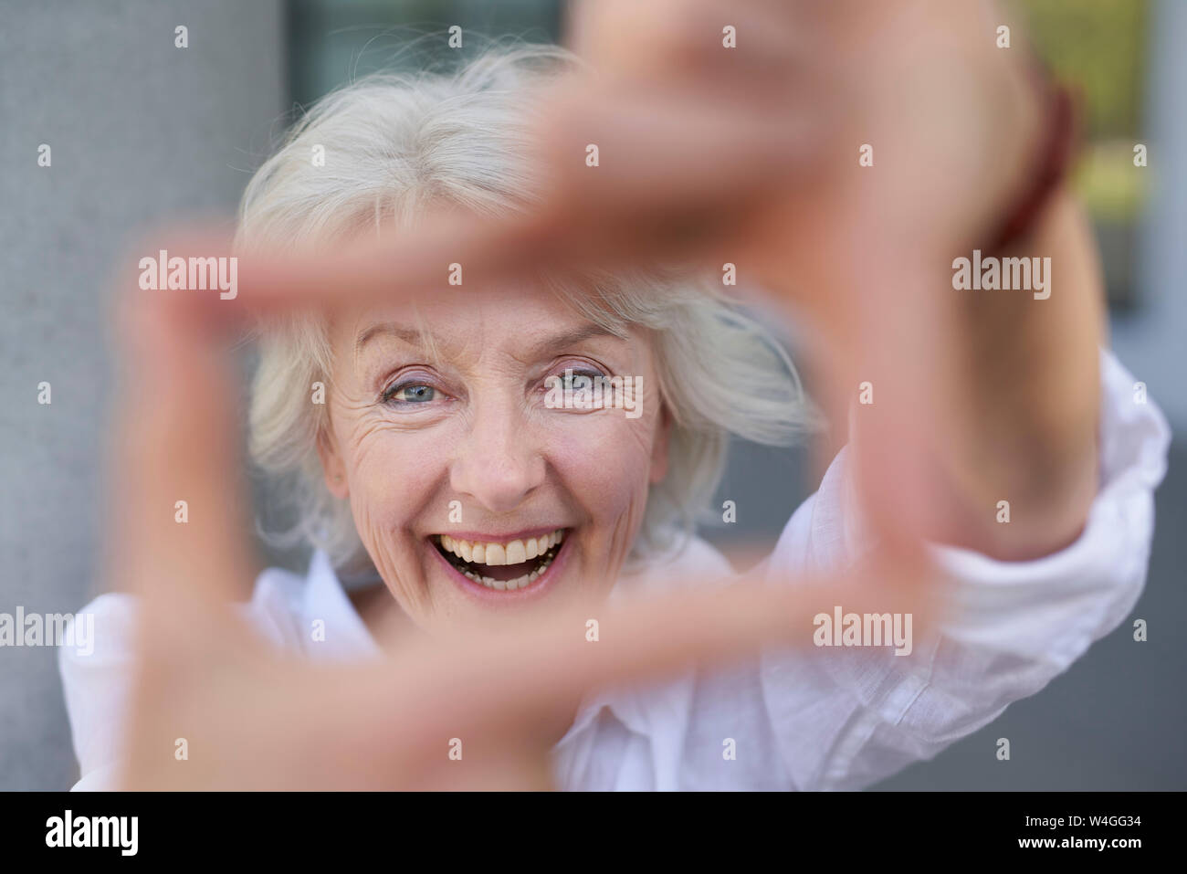 Portrait von Lachen reife Frau Gestaltung Rahmen mit Ihren Fingern Stockfoto