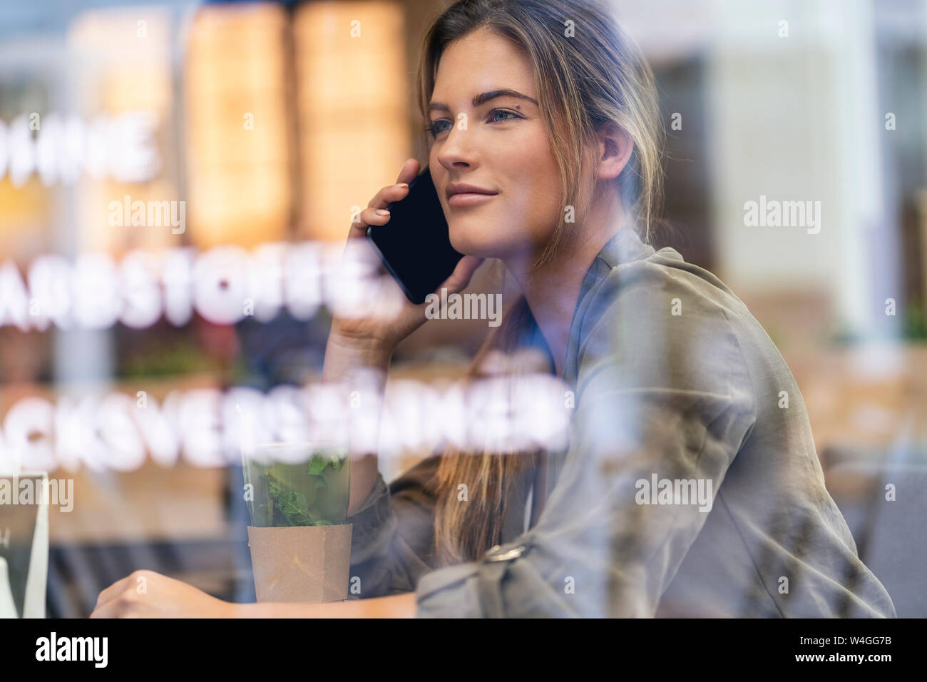 Junge Geschäftsfrau in einem Café, durch das Fenster gesehen Stockfoto