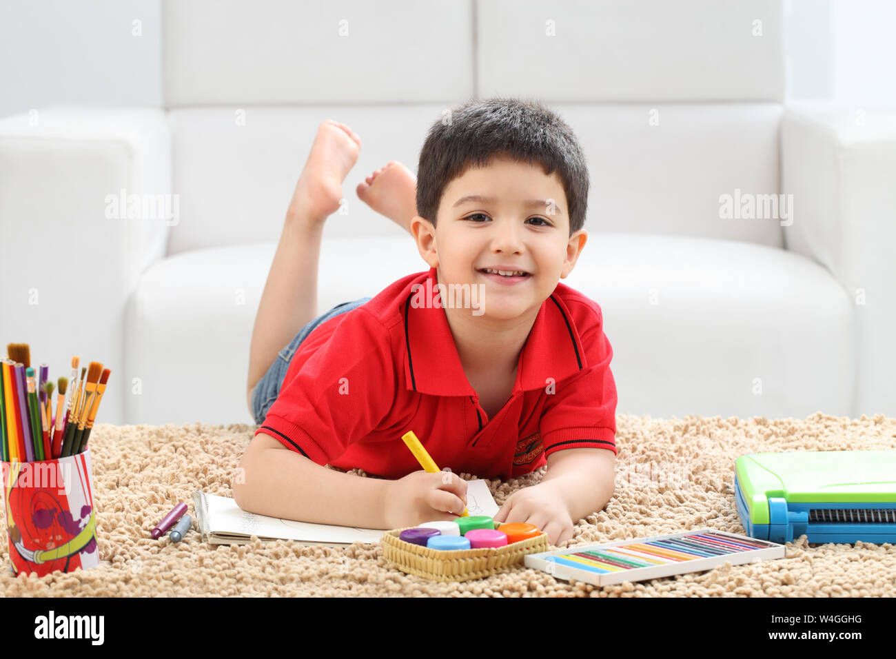 Junge, ein Malbuch und lächelnd zu Hause Stockfoto