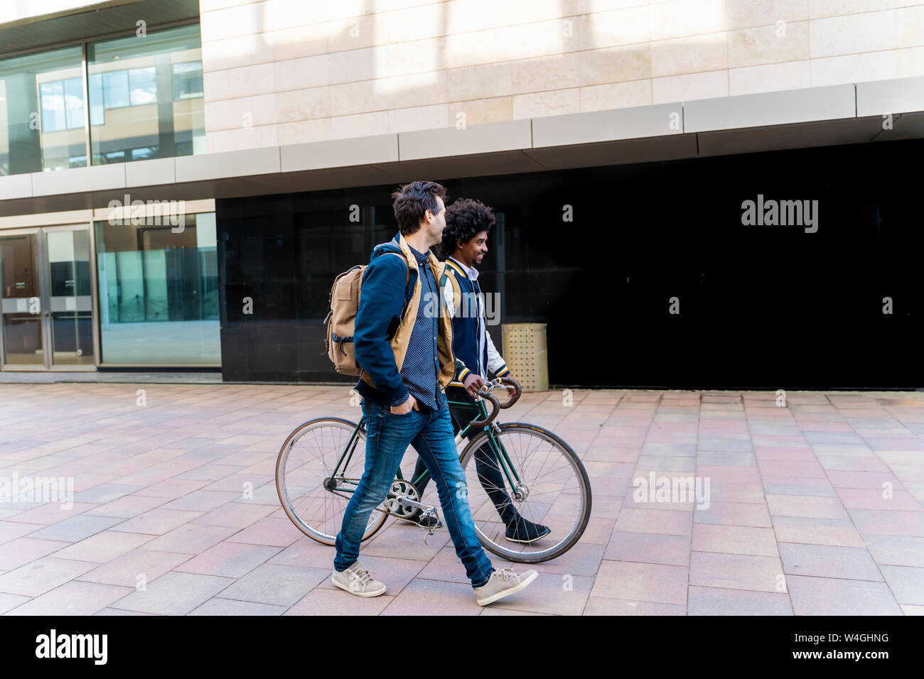 Zwei casual Geschäftsleute mit dem Fahrrad zu Fuß in die Stadt, Barcelona, Spanien Stockfoto