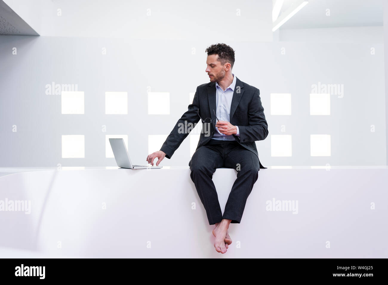 Barfuß Geschäftsmann mit Laptop im Büro Stockfoto