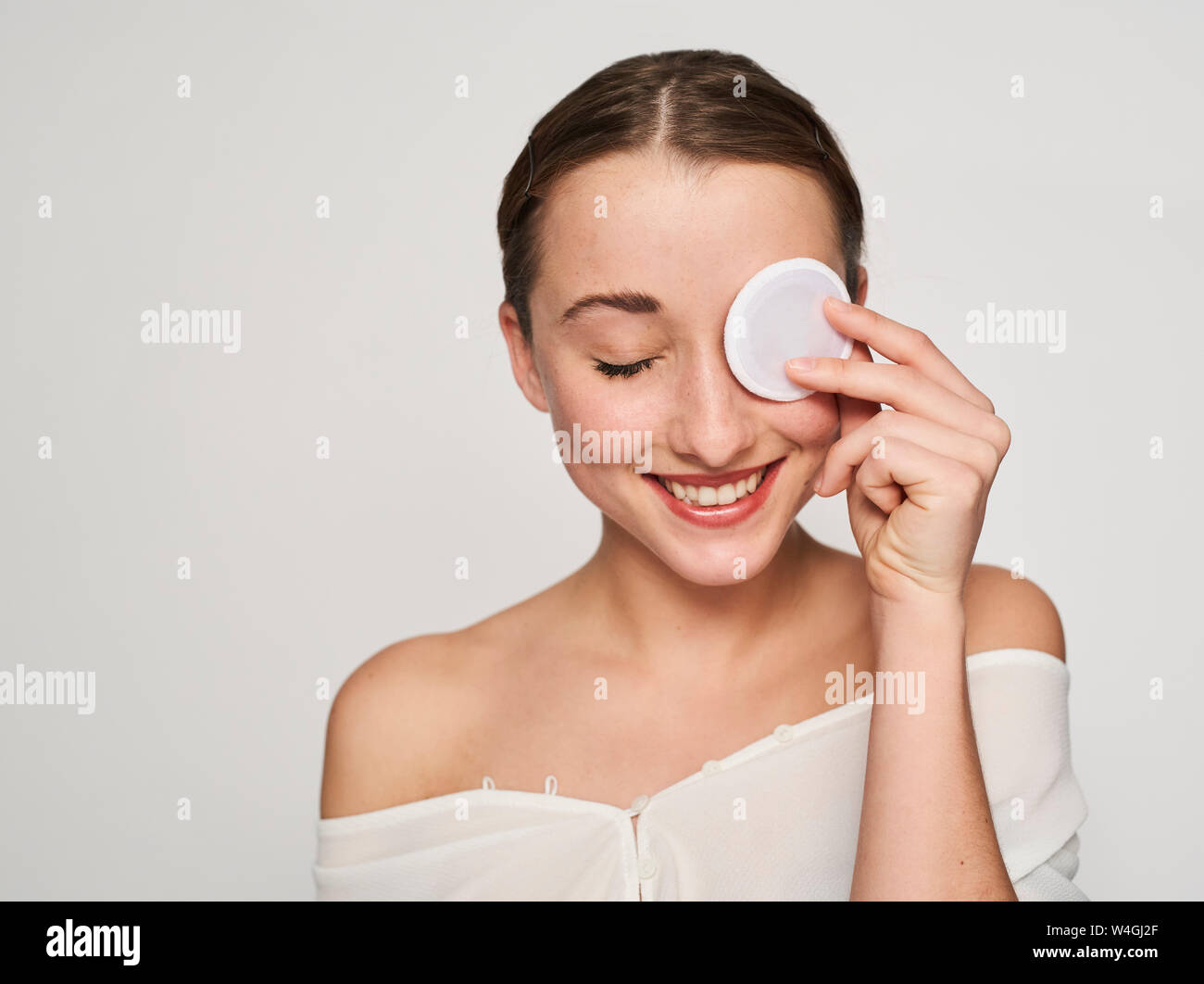 Portrait von lächelnden jungen Frau mit Baumwolle Pad auf Ihr Eve Stockfoto
