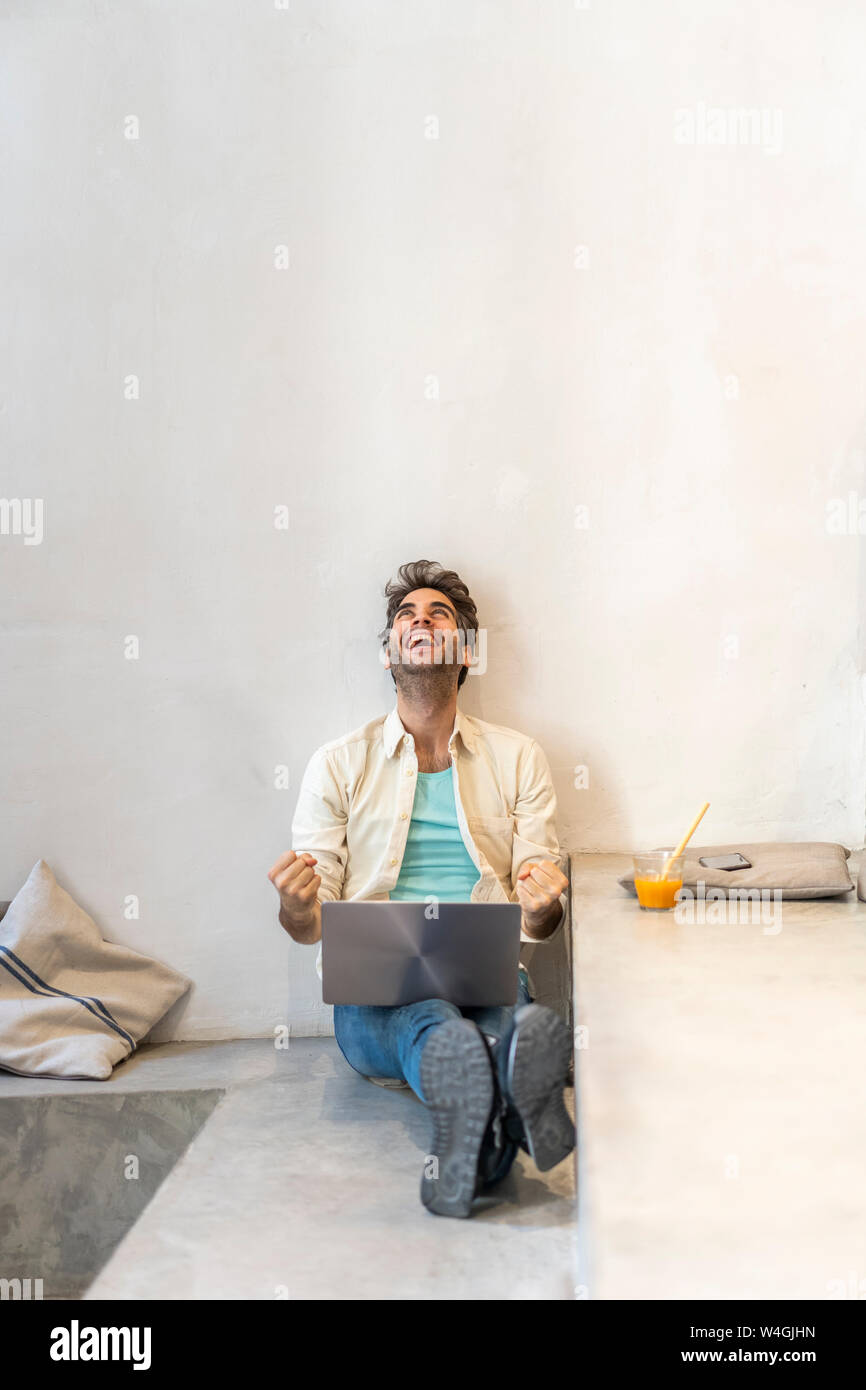 Jubelnde Menschen sitzen auf einem Schritt mit Laptop Stockfoto