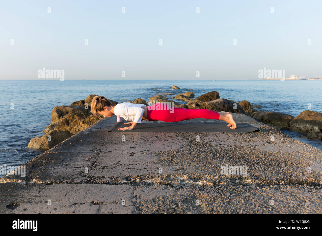 Junge Frau Yoga am Strand, chaturanga dhandasana Stockfoto