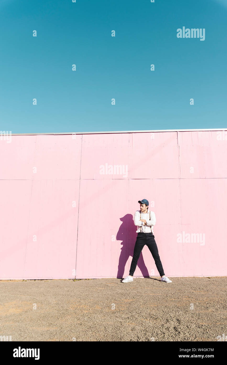Junger Mann vor rosa Bau Barriere, Weg suchen Stockfoto