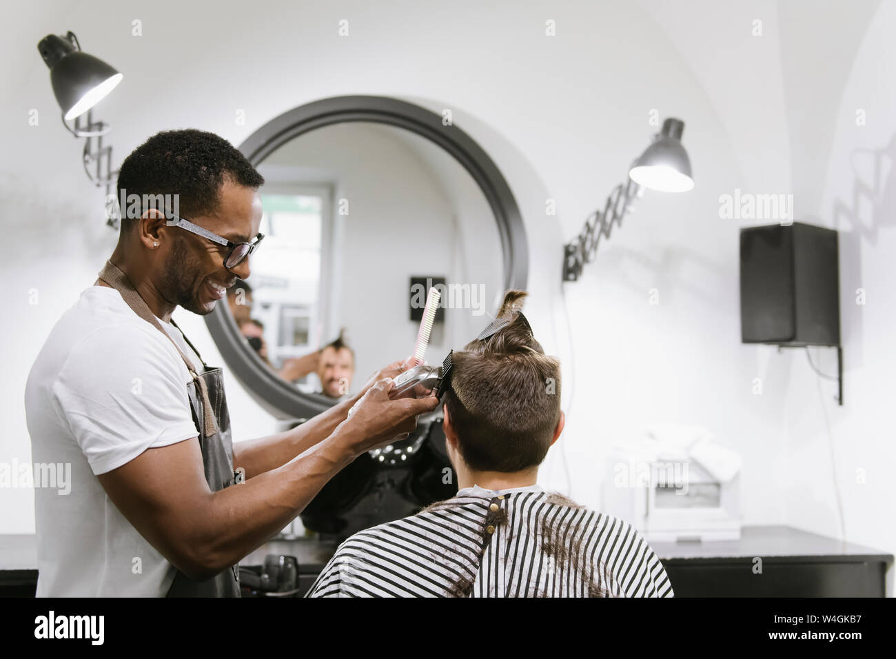 Lächelnd friseur Rasieren und Kürzen von Haaren von einem Kunden in Friseur Stockfoto
