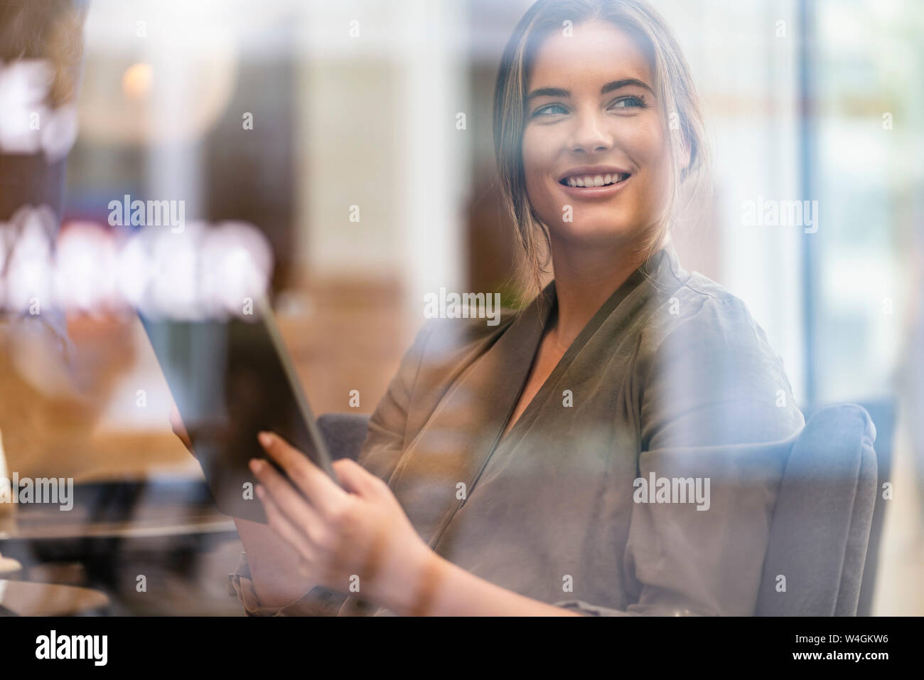Junge Geschäftsfrau in einem Café, durch das Fenster gesehen Stockfoto