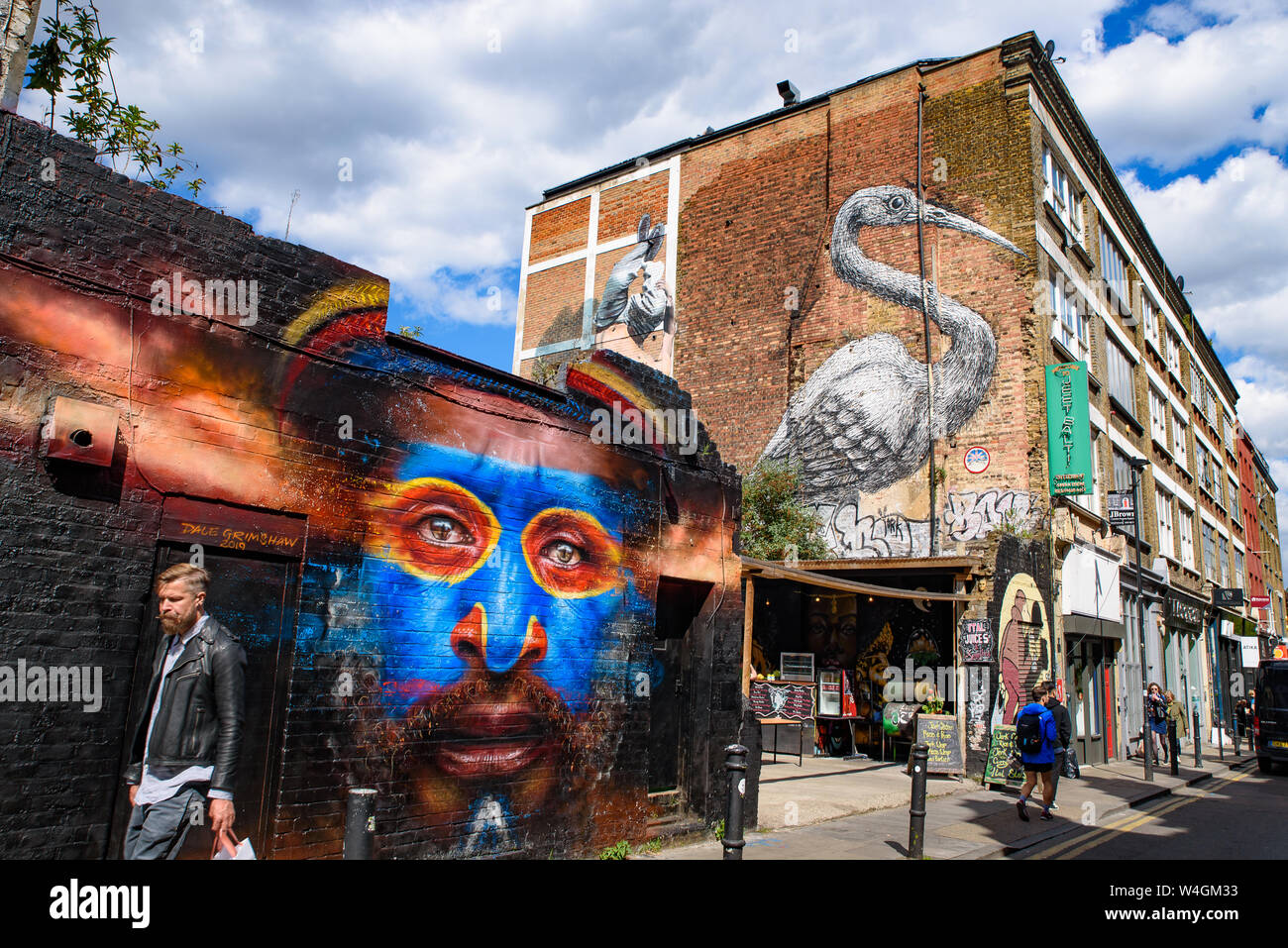 Leute, die durch die Graffiti wall Kunst an der Brick Lane Market in London, Vereinigtes Königreich Stockfoto