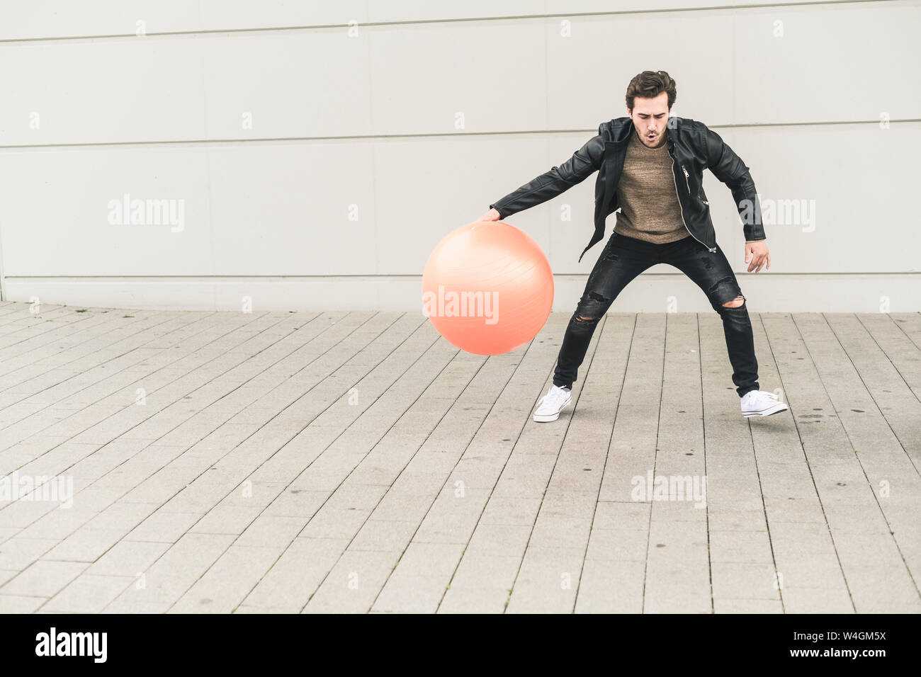 Junge Mann in der Lederjacke, Spielen mit einem Gymnastikball Stockfoto