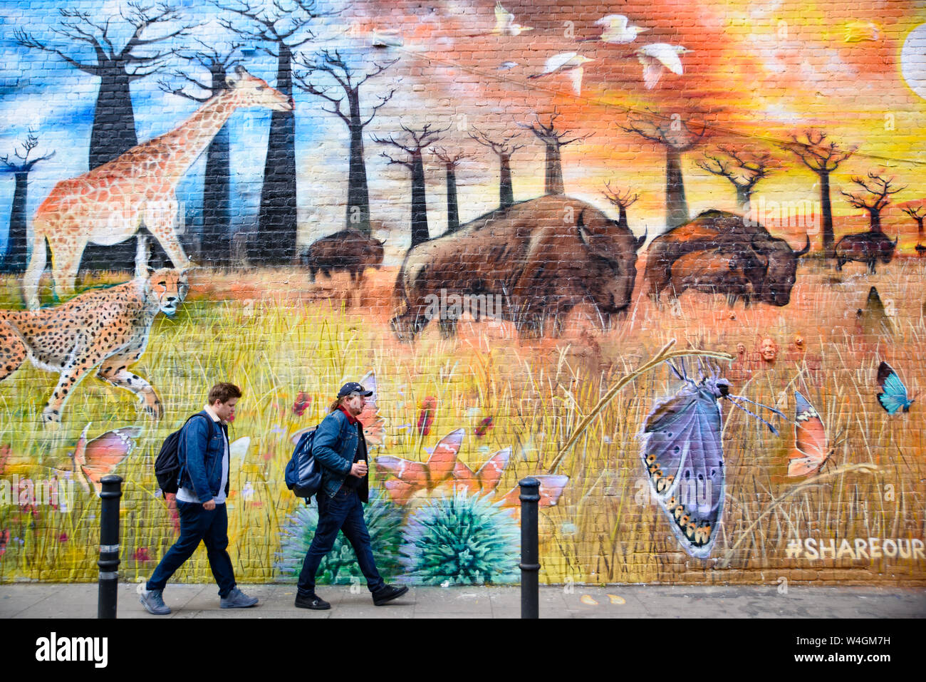 Leute, die durch die Graffiti wall Kunst an der Brick Lane Market in London, Vereinigtes Königreich Stockfoto