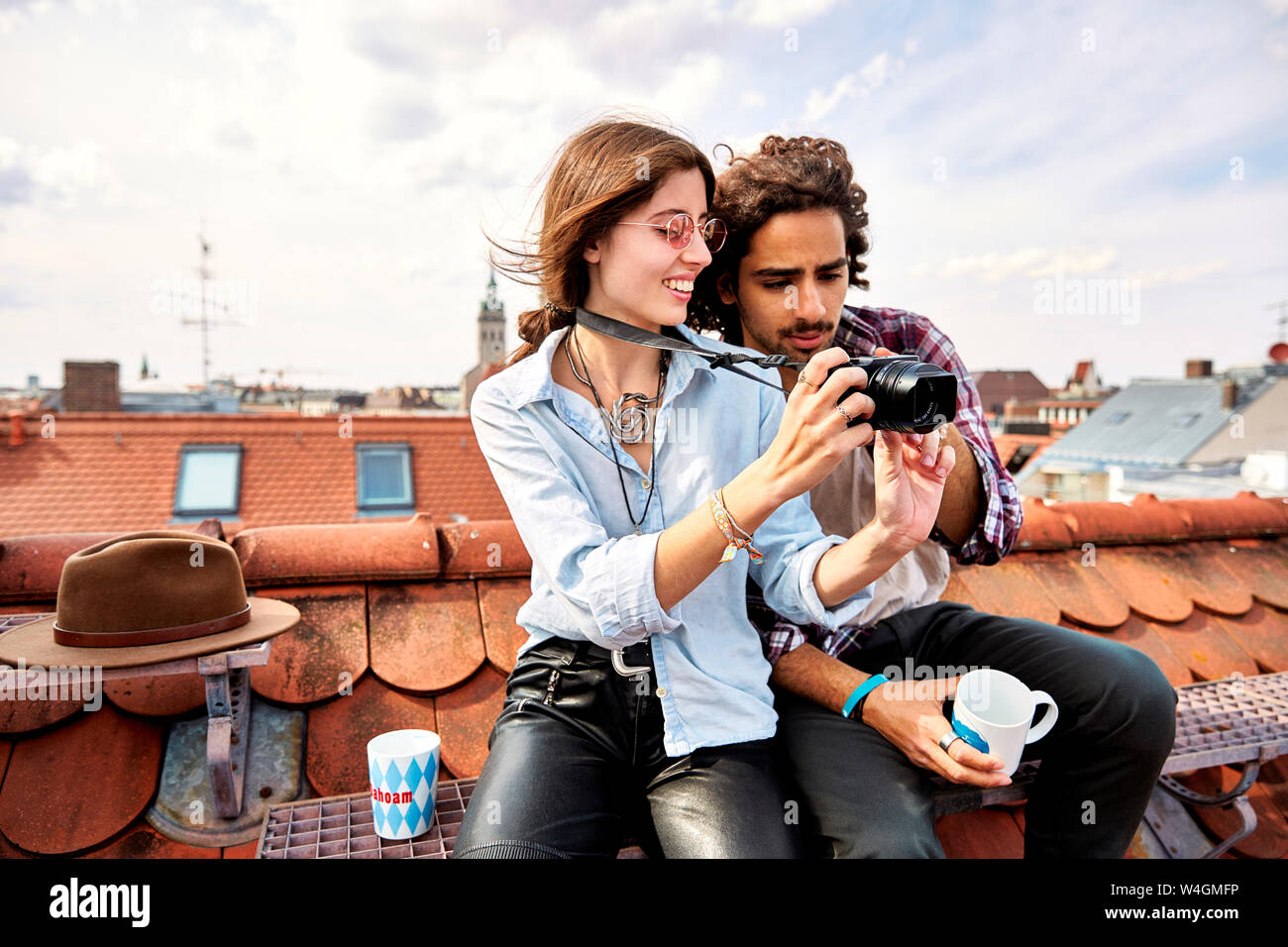 Junges Paar sitzt auf dem Dach und Bilder aufnehmen Stockfoto