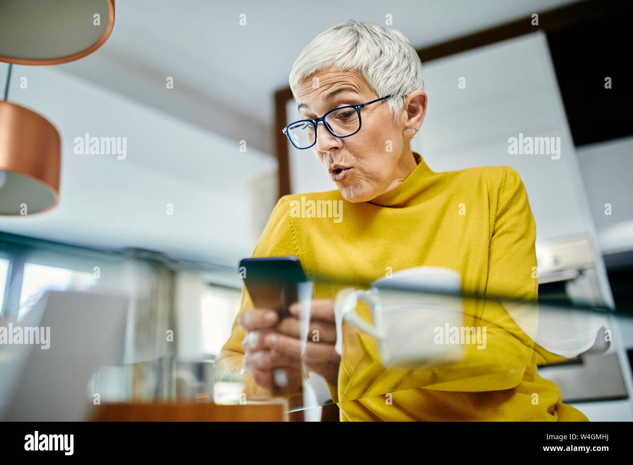 Ältere Frau trinkt Kaffee, Kontrolle SMS-Nachrichten auf Ihrem Smartphone Stockfoto