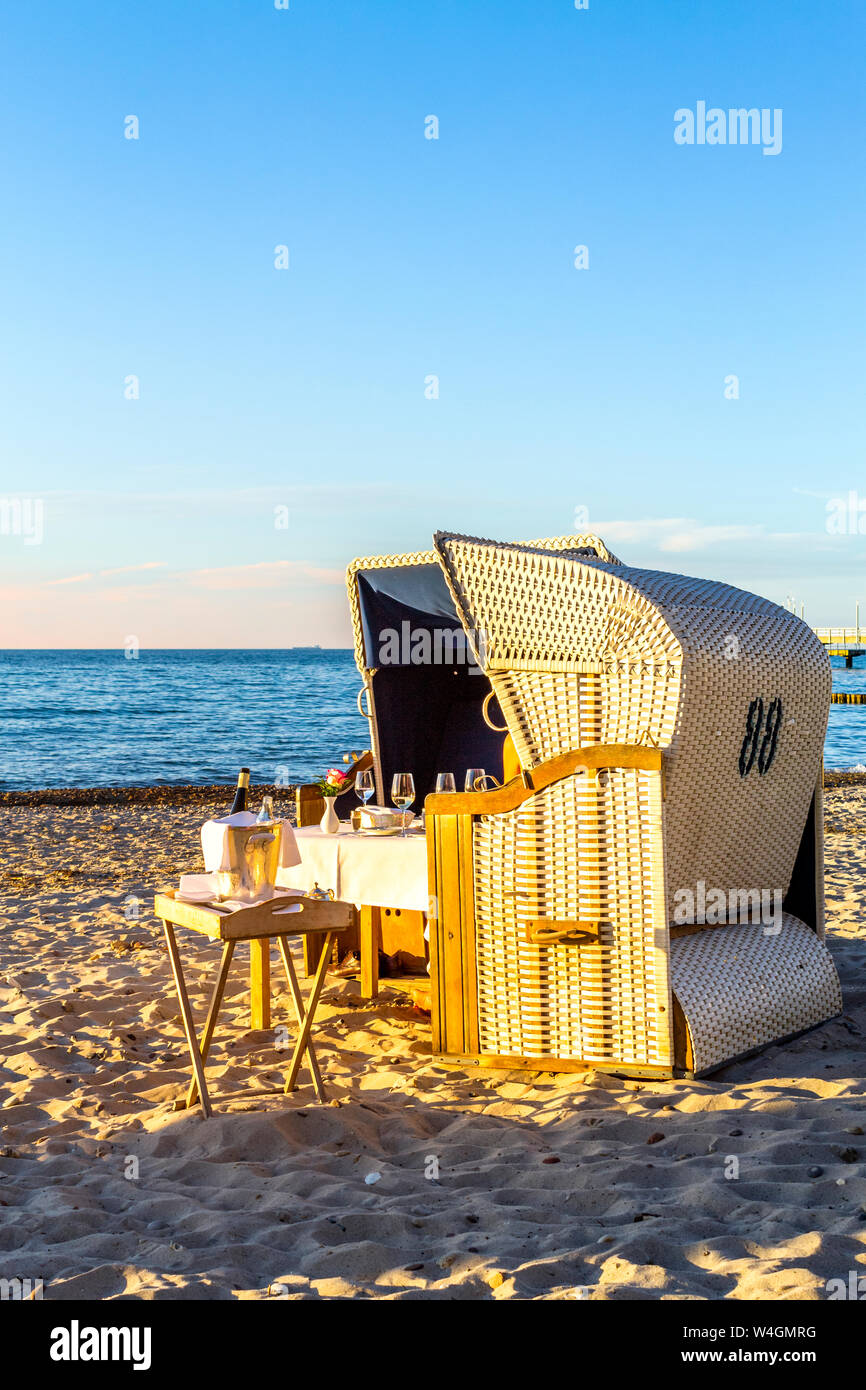 Gedeckter Tisch und mit Kapuze liegen am Strand am Abend, Heiligendamm, Deutschland Stockfoto