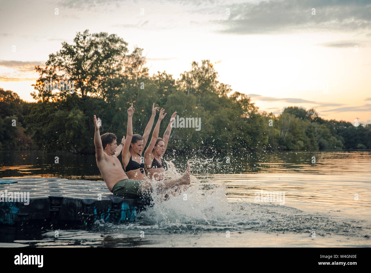 Freunde Spaß am See, sitzen auf Badeplattform, slpashing Wasser Stockfoto