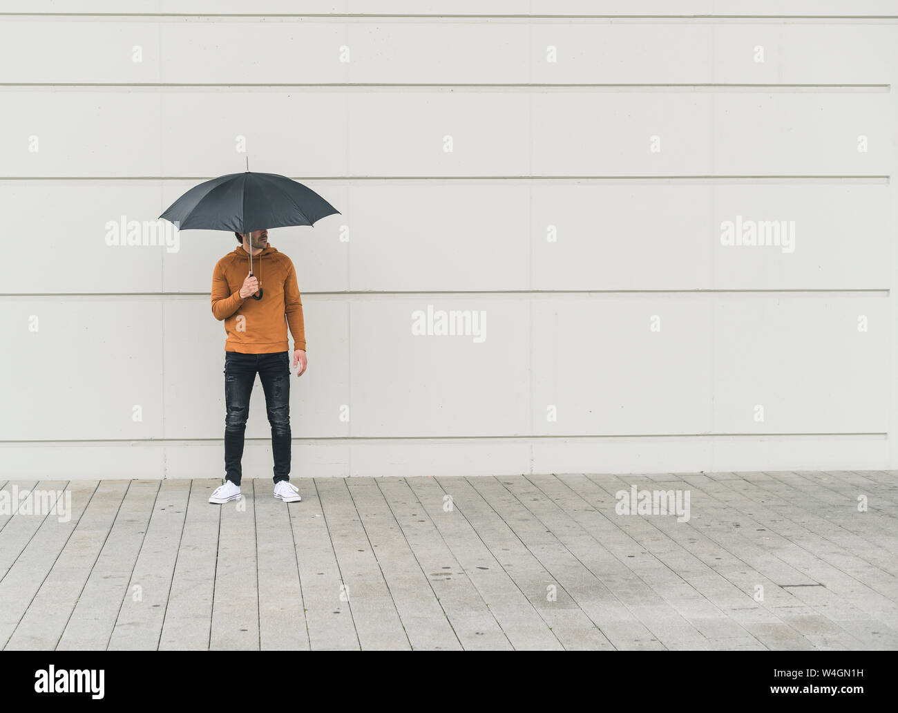 Junger Mann mit Schirm auf der Straße Stockfoto