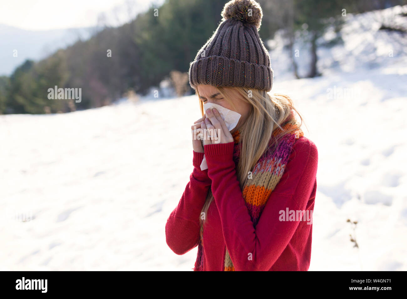 Junge blonde Frau blasen Nase im Winter Stockfoto