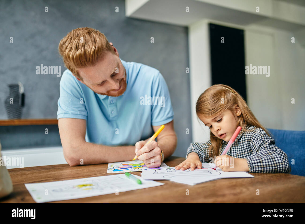 Vater und Tochter am Tisch sitzen, malen Buch Färbung Stockfoto