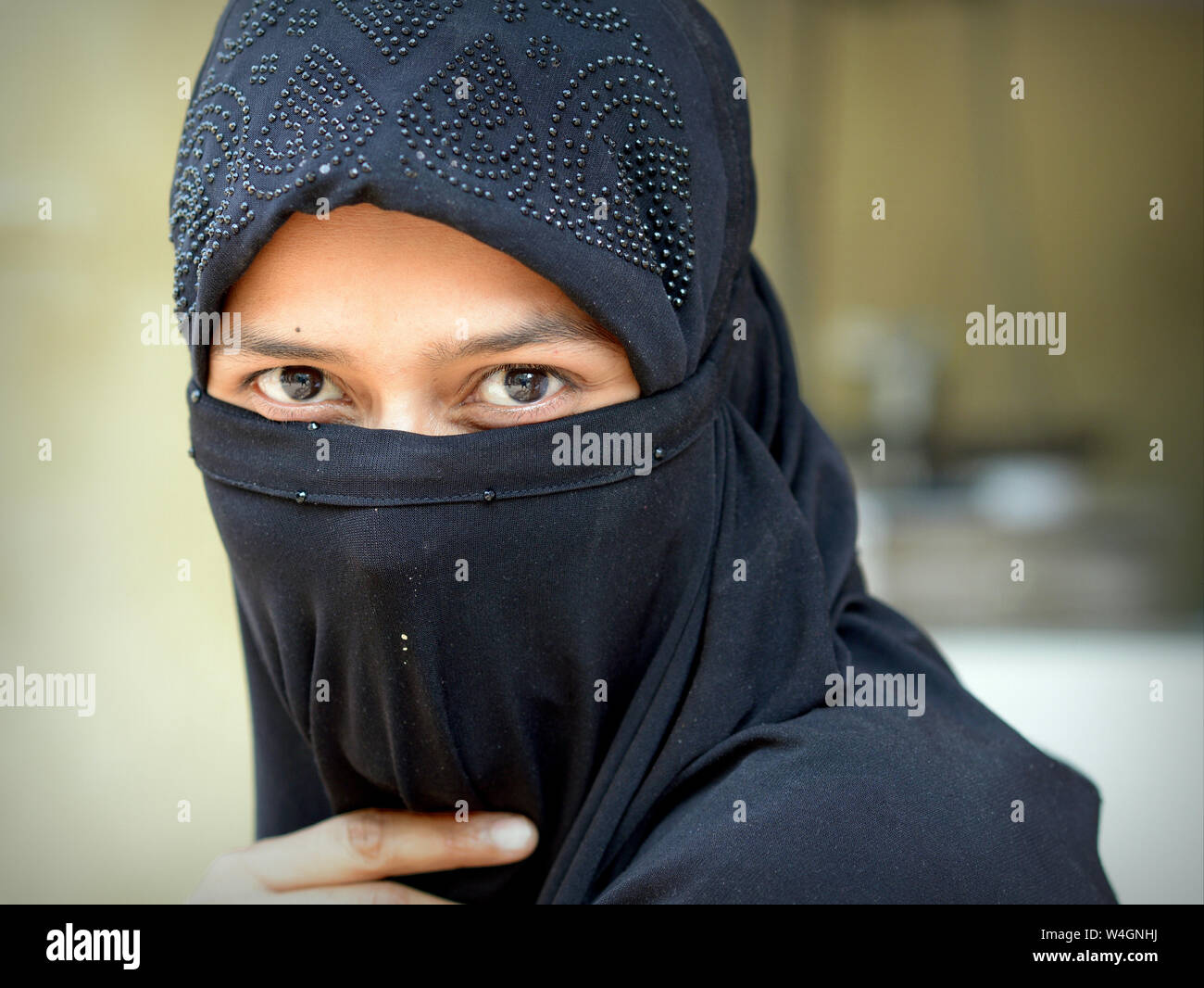 Junge indische Muslima mit schönen Augen deckt ihr Haar und der untere Teil des Gesichts mit einem schwarzen islamischen Schleier (Niqab). Stockfoto