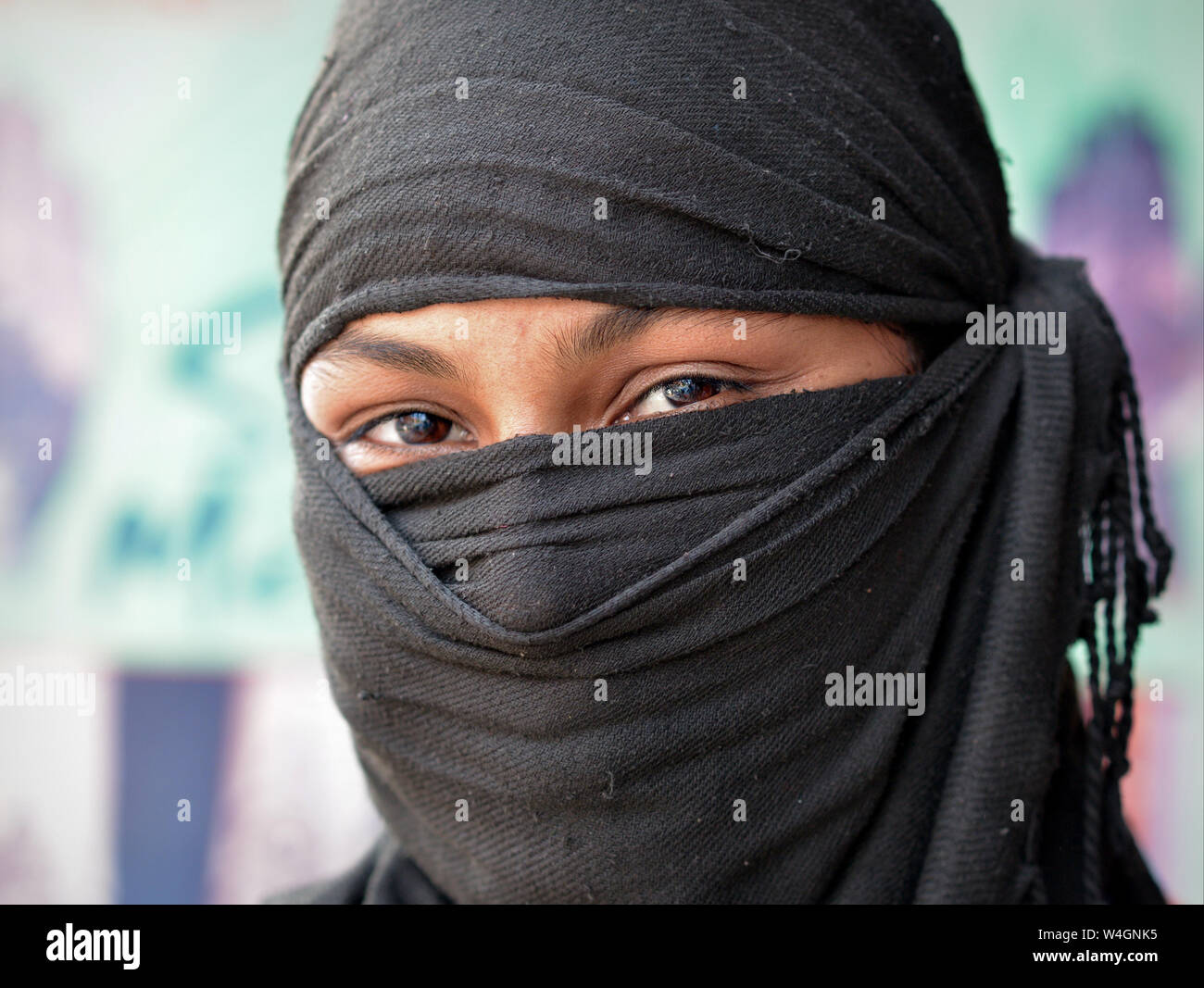 Junge indische Muslima mit schönen Augen deckt den Rest von ihr Gesicht mit einem schwarzen Kopftuch. Stockfoto