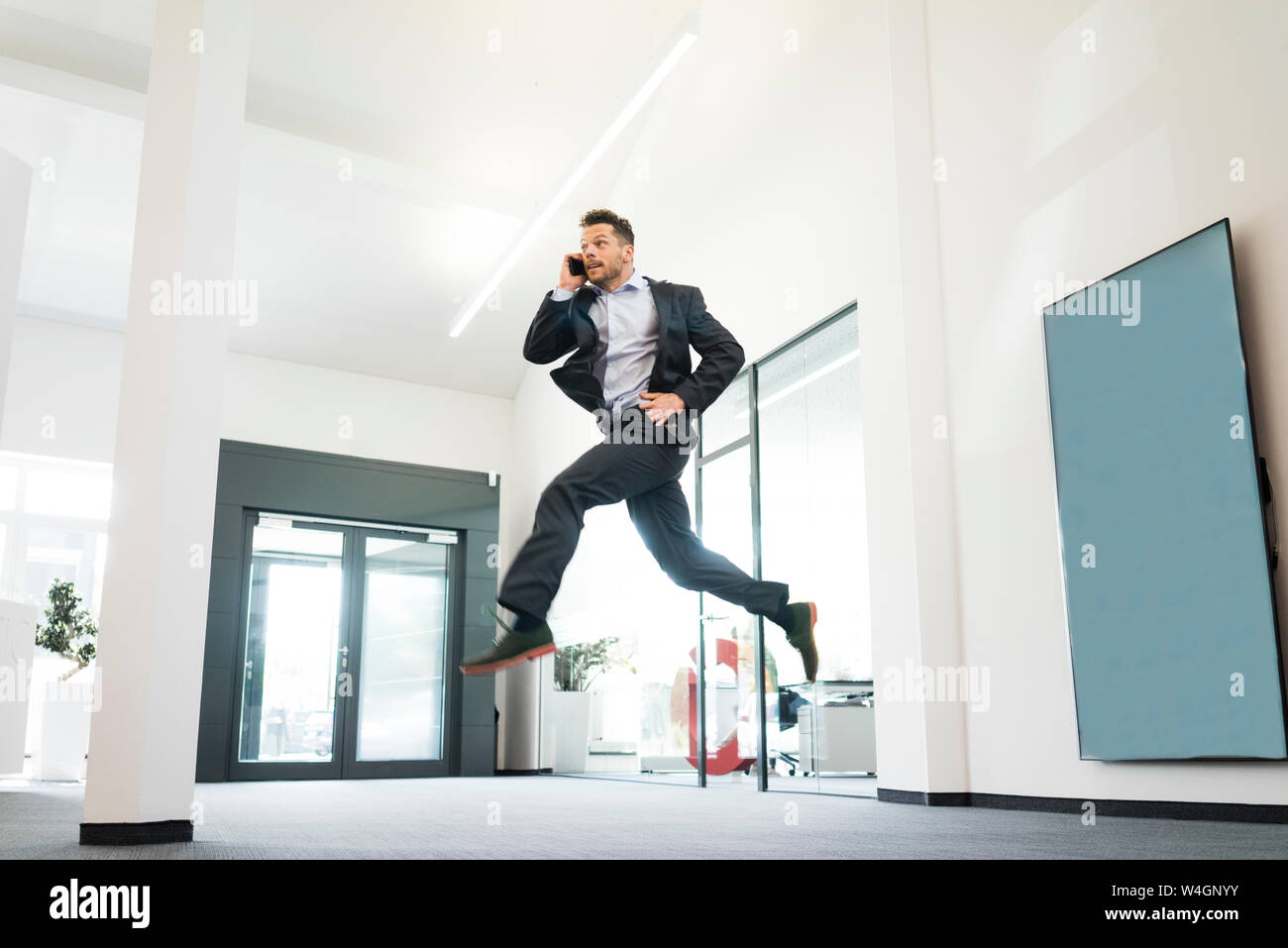 Geschäftsmann auf Handy springen im Büro Stockfoto