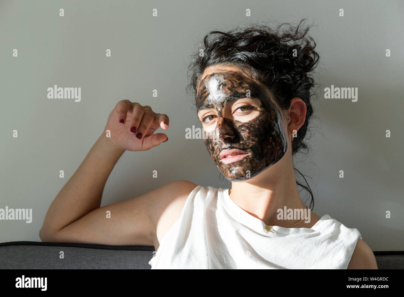 Porträt der jungen Frau mit Gesichtsmaske zu Hause Stockfoto