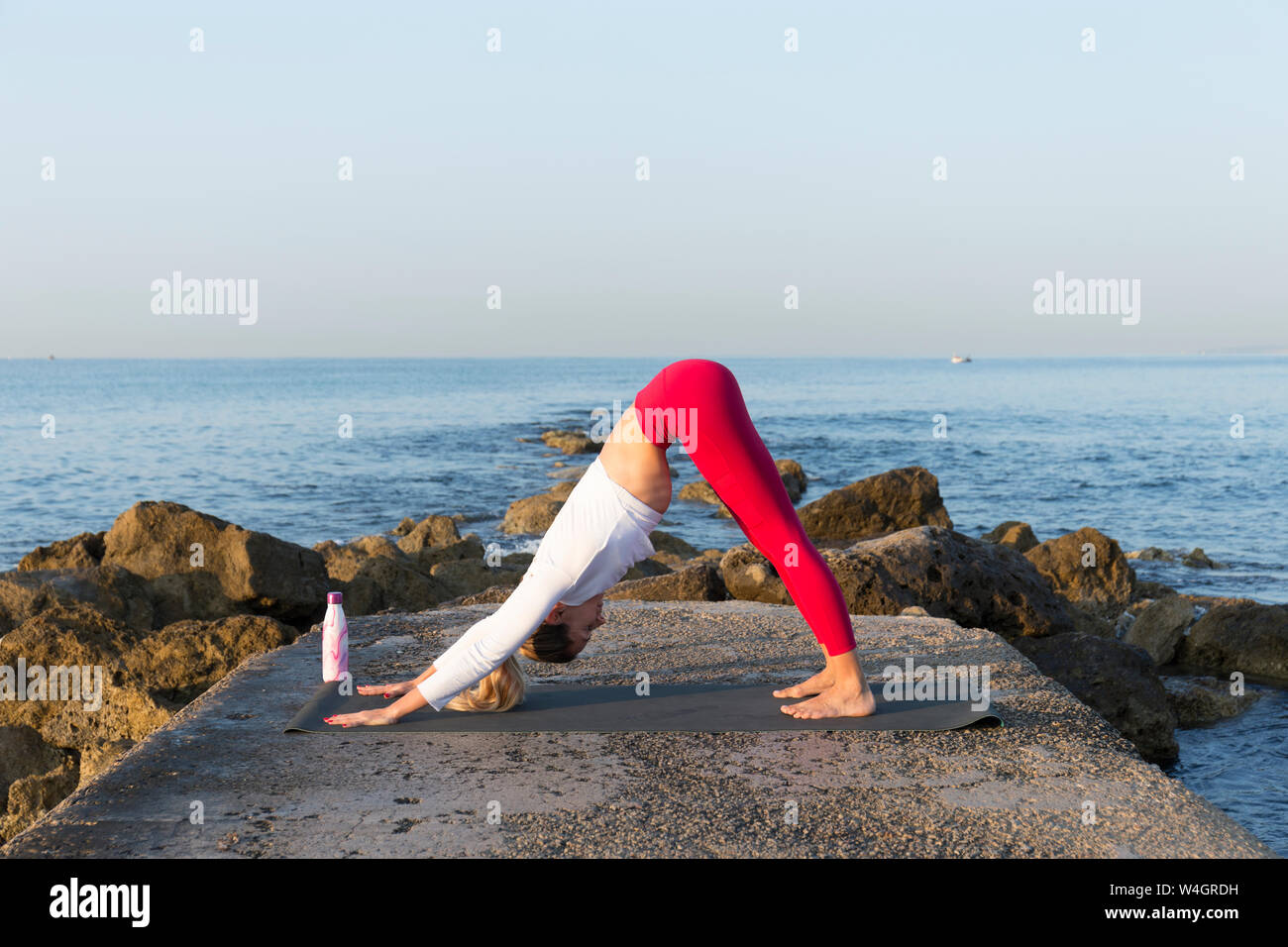 Junge Frau Yoga am Strand, den nach unten schauenden Hund. Stockfoto
