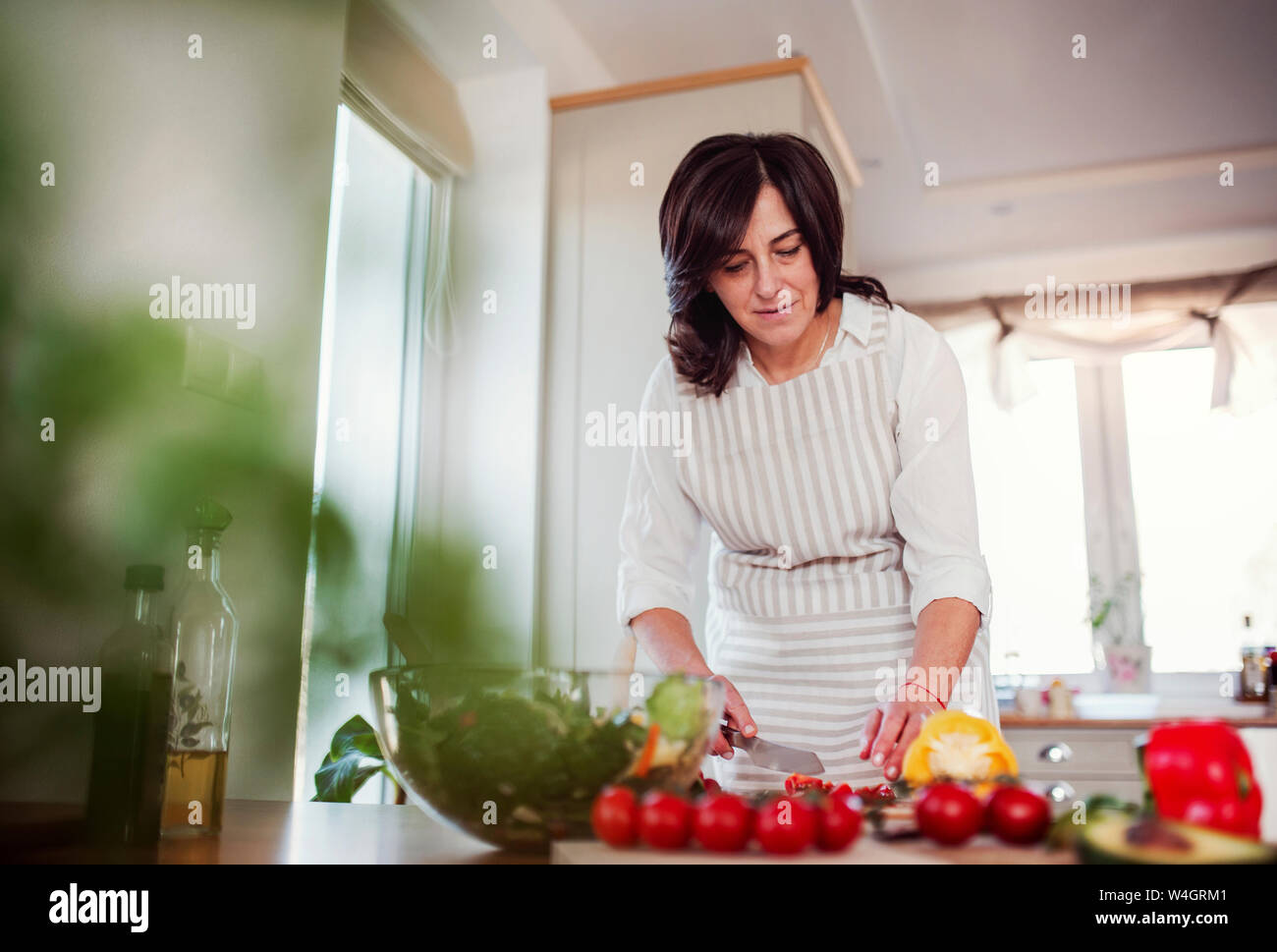 Reife Frau Zubereitung Salat in Ihrer Küche Stockfoto