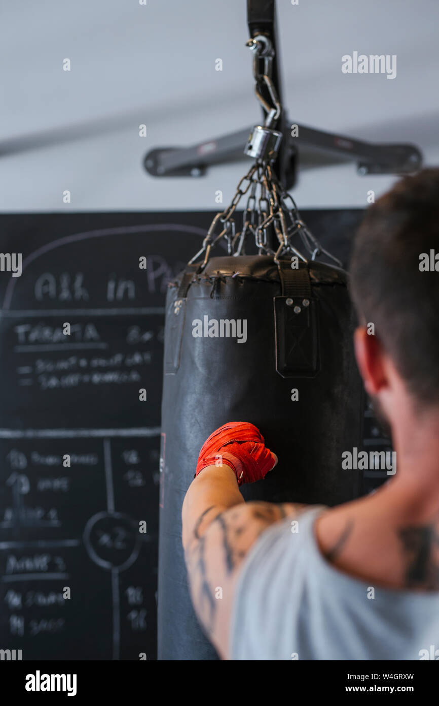 Junger Mann Boxen gegen Boxsack Stockfoto