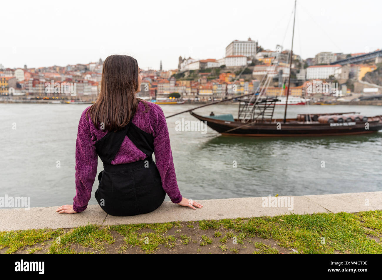 Rückansicht der jungen Frau vor dem Fluss Douro, Porto, Portugal sitzen Stockfoto