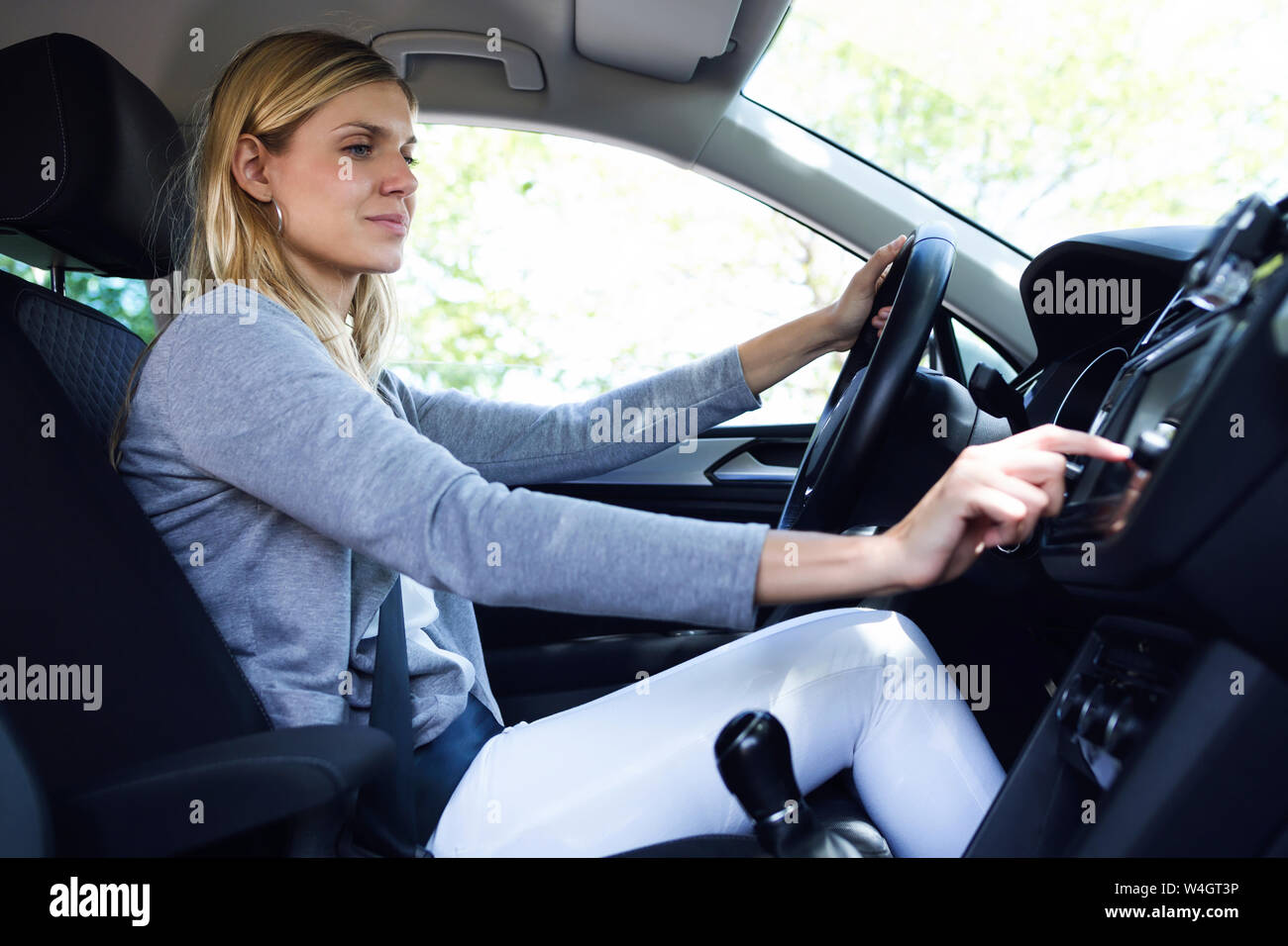 Junge Frau Treiber Auswahl eines Radiosenders in Ihrem Auto Stockfoto