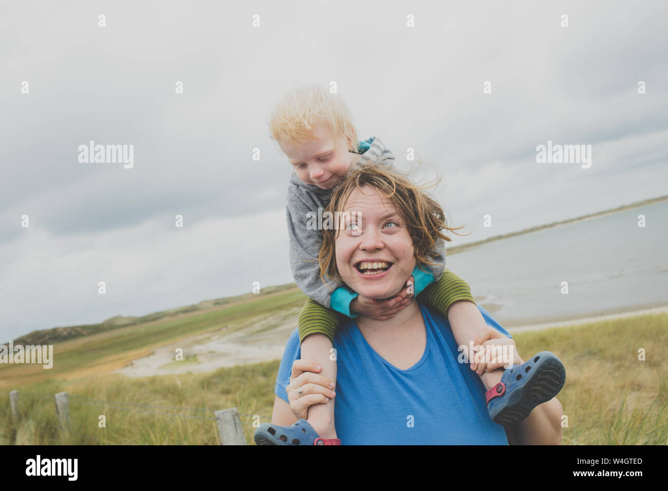 Portrait der glücklichen Mutter, die kleine Tochter auf ihren Schultern, Sylt, Deutschland Stockfoto