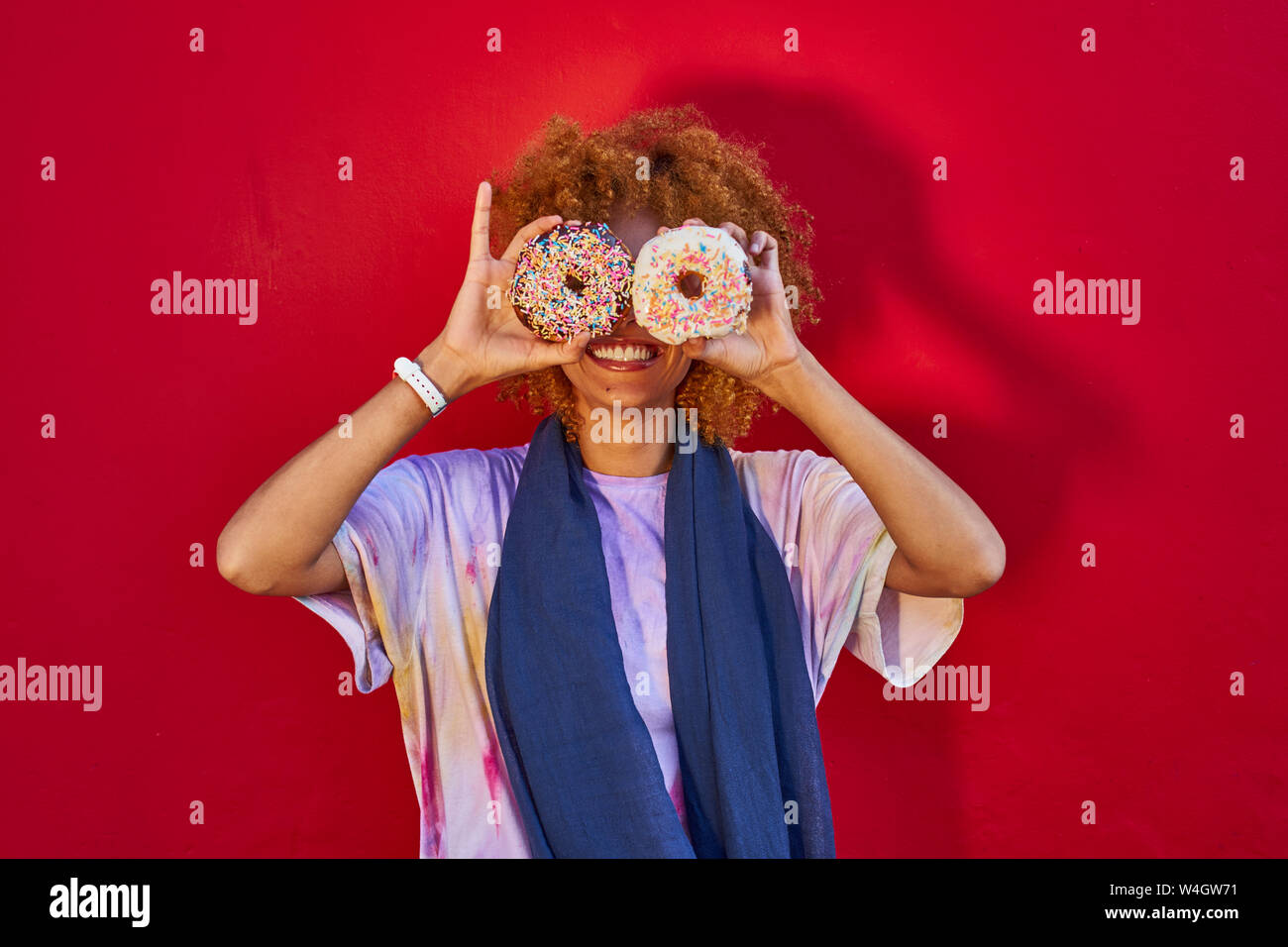 Verspielte Frau mit zwei Donuts, der vor ihren Augen Stockfoto