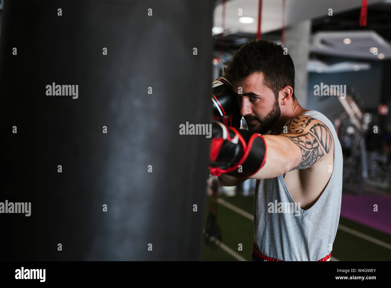 Junger Mann in Boxhandschuhe gegen Boxsack Stockfoto