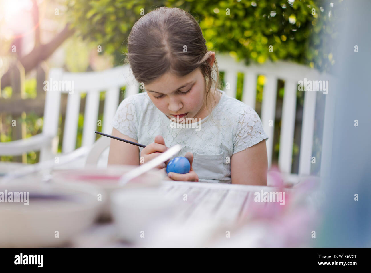 Mädchen Malerei Osterei auf Garten Tisch Stockfoto
