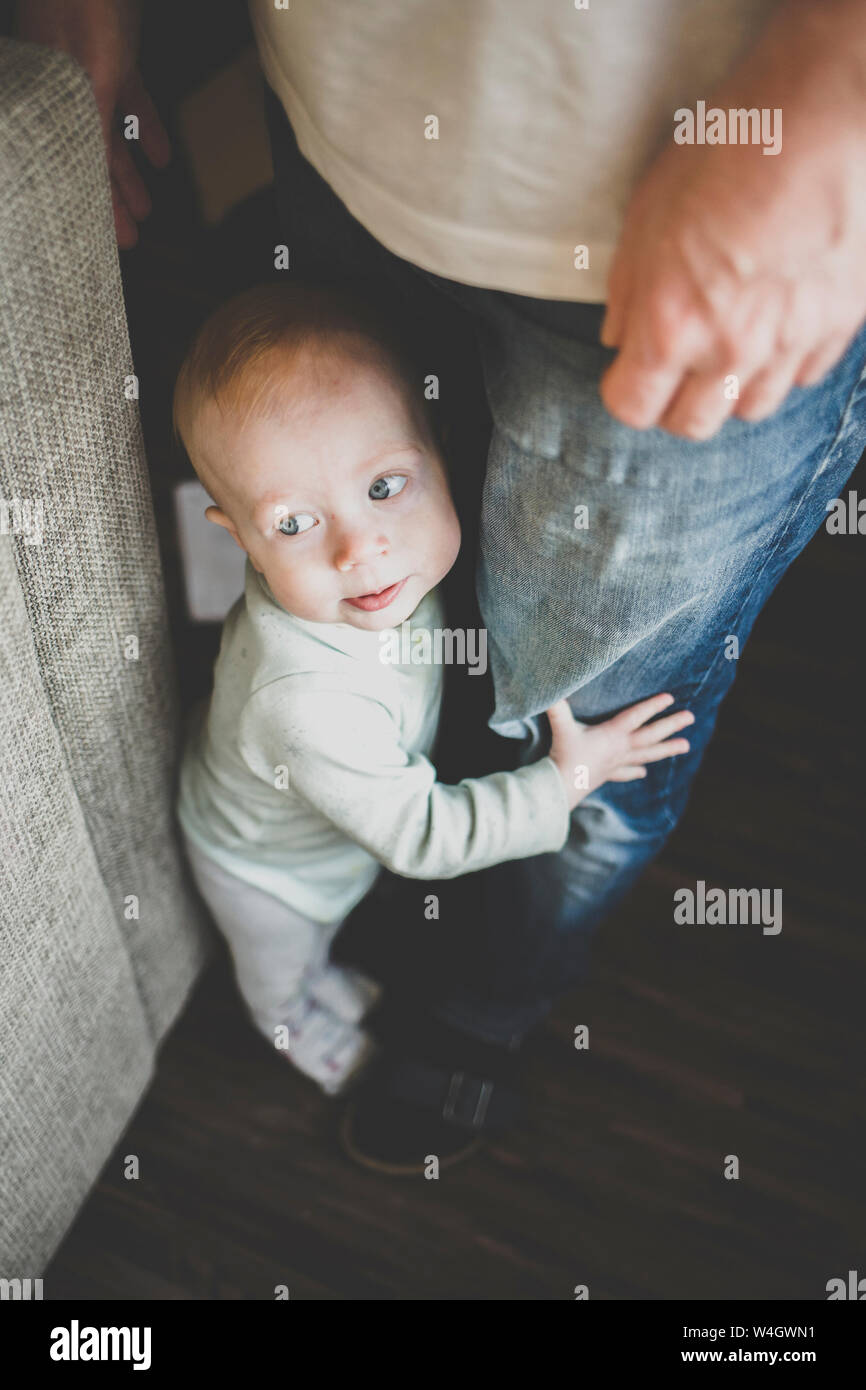 Baby Mädchen, das versuchte aufrecht Jeans ihres Vaters halten zu stehen Stockfoto