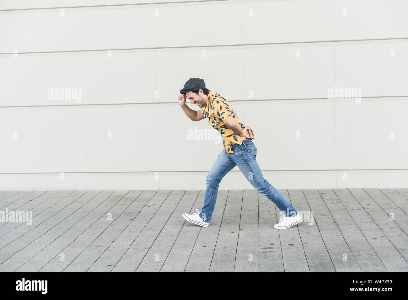 Junger Mann, der flache Hut und Aloa Shirt, Wandern gegen Gegenwind Stockfoto