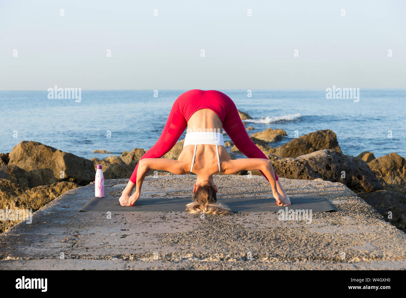 Junge Frau Yoga am Strand, prasarita padottanasana Stockfoto