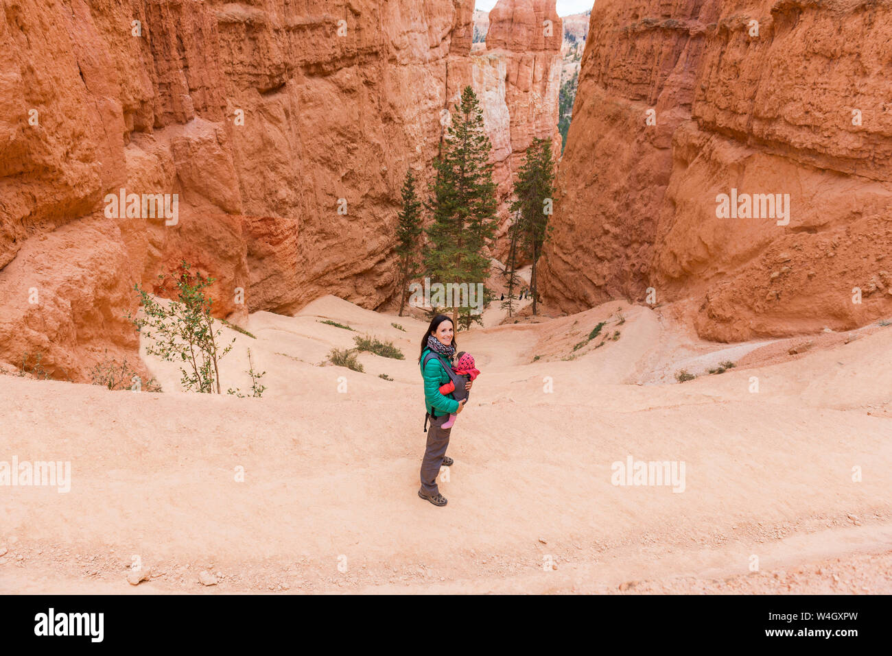 Frau, die ihre Tochter in einem tragesitz bei Hoodoos im Bryce Canyon, Utah, USA Stockfoto