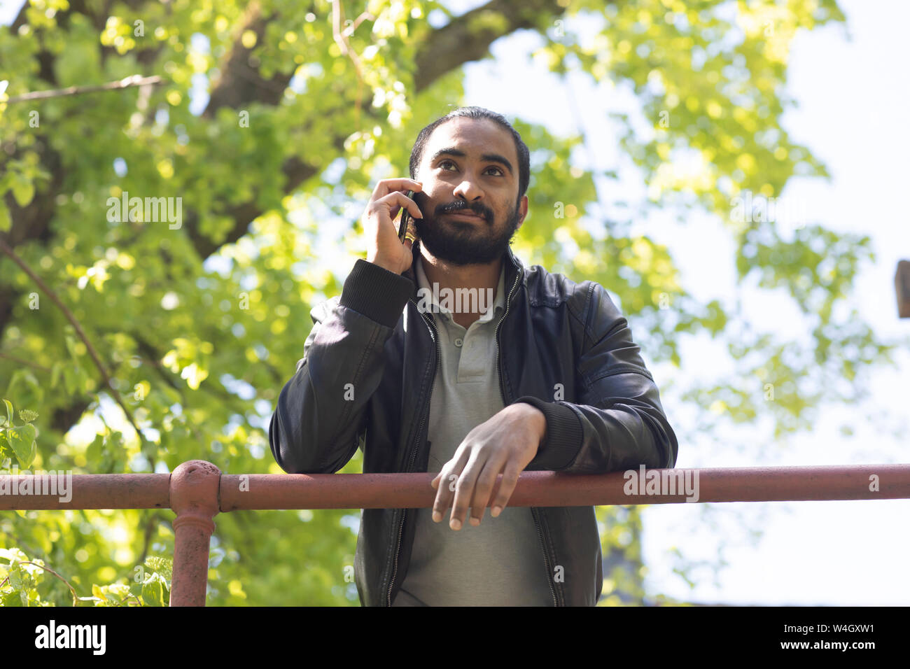 Portrait von bärtiger junger Mann am Telefon im Freien Stockfoto