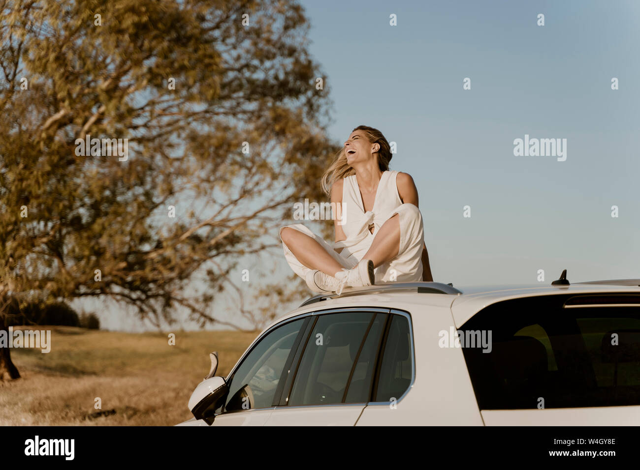 Lachend weibliche Reisende sitzen auf weißes Auto Dach Stockfoto