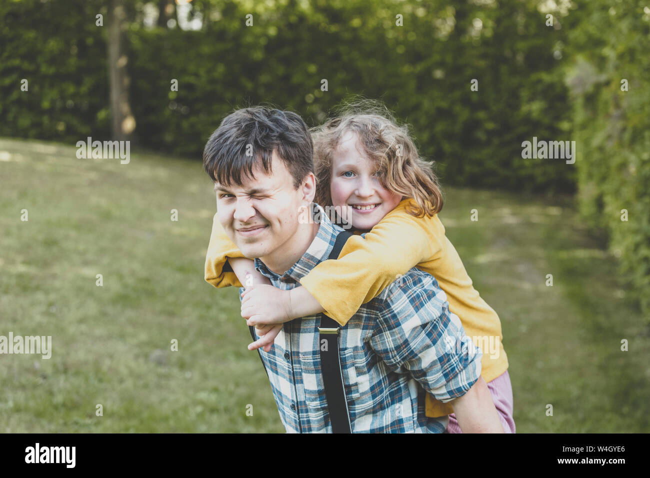 Eine lächelnde Mädchen reiten auf ihren großen Bruder zurück Stockfoto