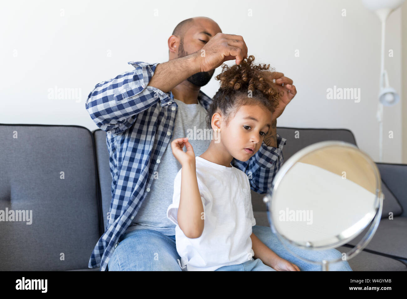 Vater tun Haare's Tochter auf der Couch zu Hause Stockfoto